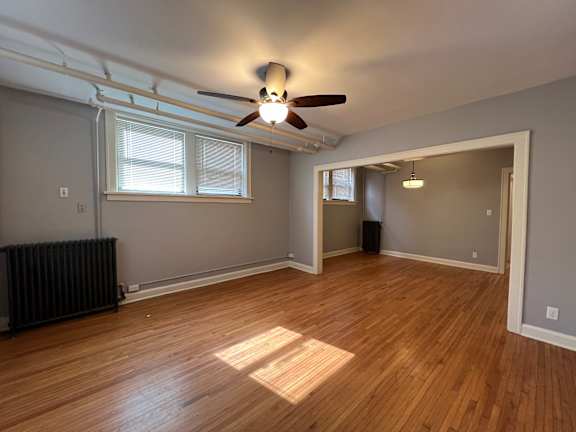 A room with a ceiling fan and wooden flooring.