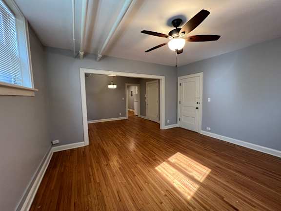 A room with a ceiling fan and wooden flooring.