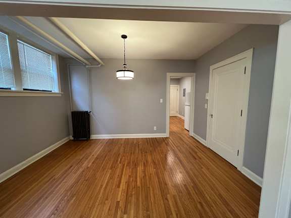 A room with wooden floors and a hanging light fixture.