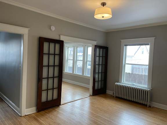 A room with a window, a door, and a radiator.