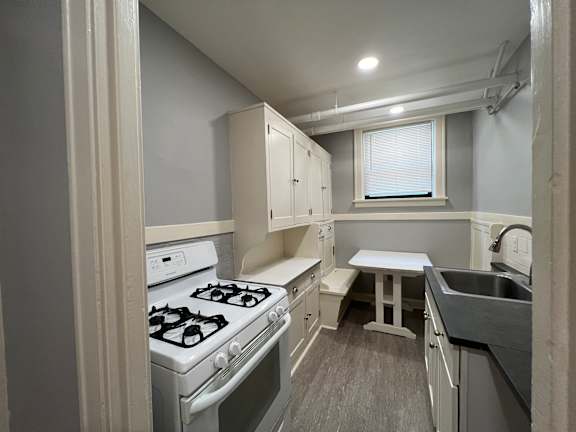 A small kitchen with a stove, sink, and table.