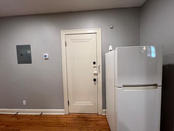 A white door is in a room with a white fridge.