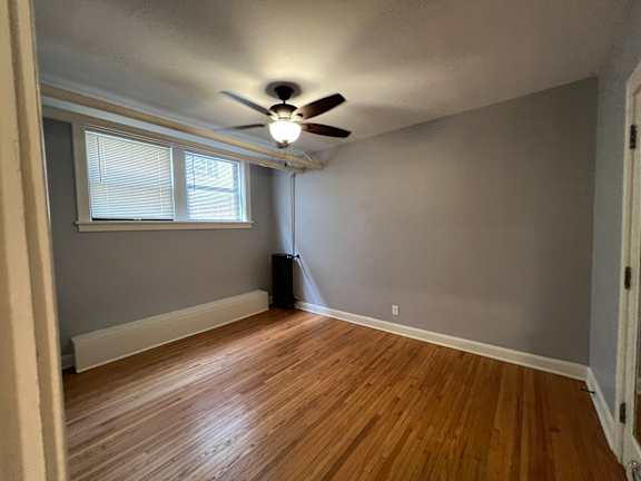 A room with a ceiling fan and wooden flooring.