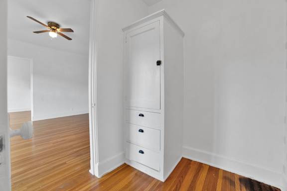 A white closet with a ceiling fan and a drawer is in the room.