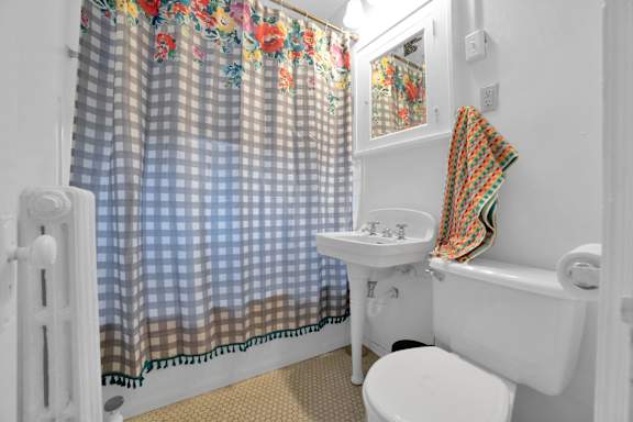 A small bathroom with a toilet, sink, and shower curtain.