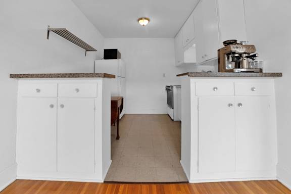 A kitchen with white cabinets and a wooden floor.