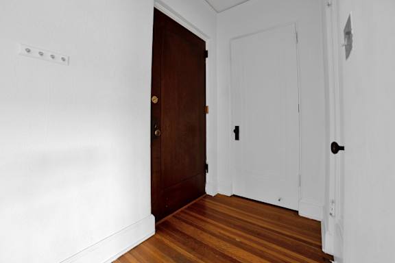 A hallway with a brown door and a white door.