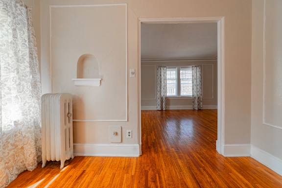 A room with a white radiator and wooden floors.