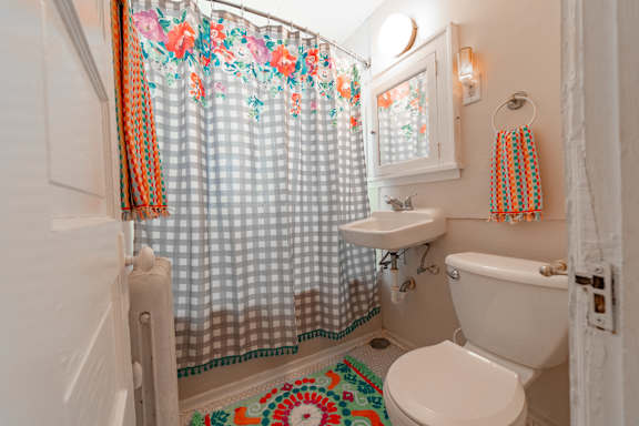 A white toilet sits next to a sink in a bathroom with a floral shower curtain.