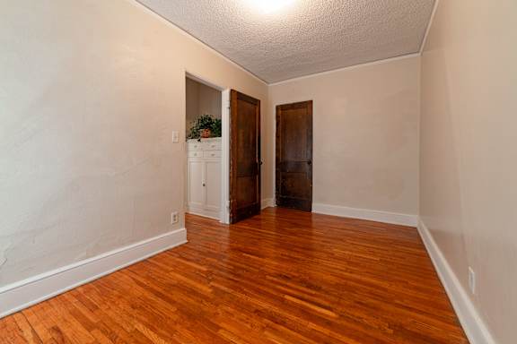 A room with wooden floors and two doors.