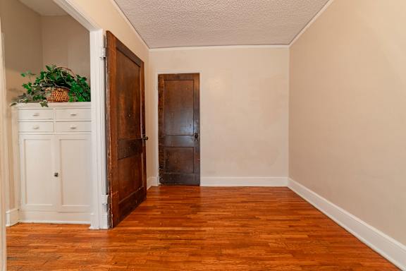 A room with a wooden floor and a white cabinet with a plant on top.