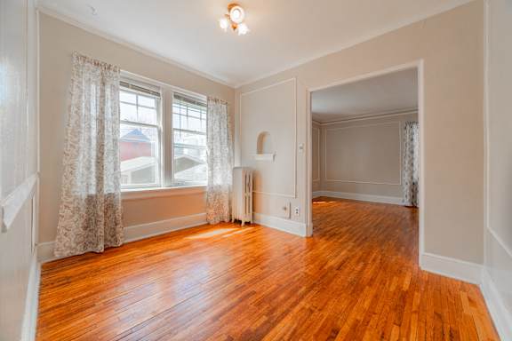 A room with wooden floors and a window with curtains.