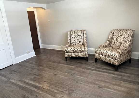 Two leopard print chairs are placed in a room with wooden flooring.