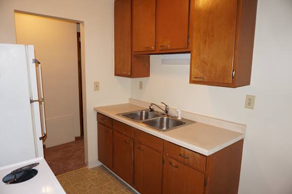 A kitchen with brown cabinets and a white fridge.