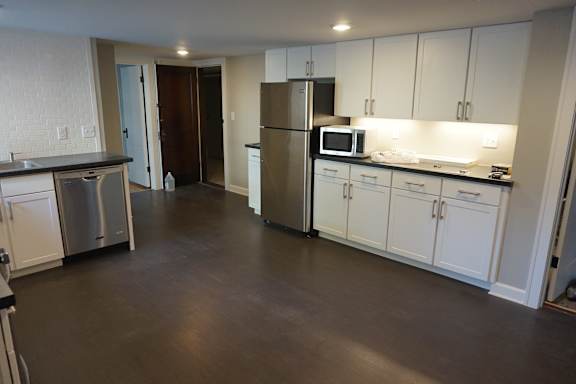 A kitchen with white cabinets and a stainless steel refrigerator.