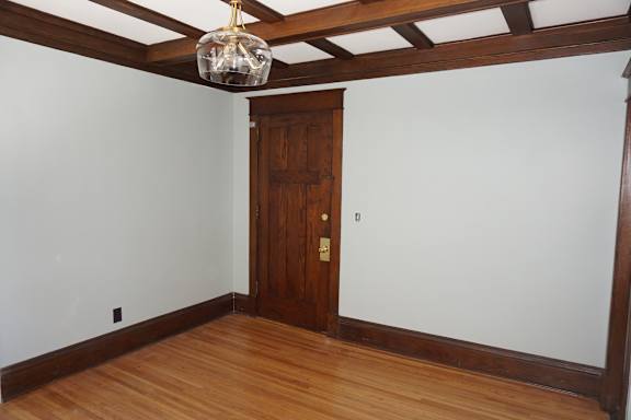 A room with a wooden door and a light hanging from the ceiling.