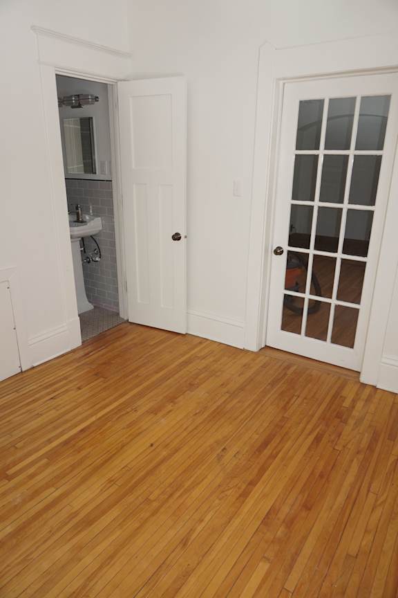 A white door is open to a bathroom with a white sink and a white cabinet.