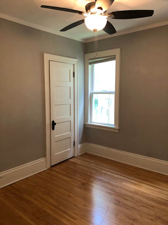 A room with a ceiling fan and a door.