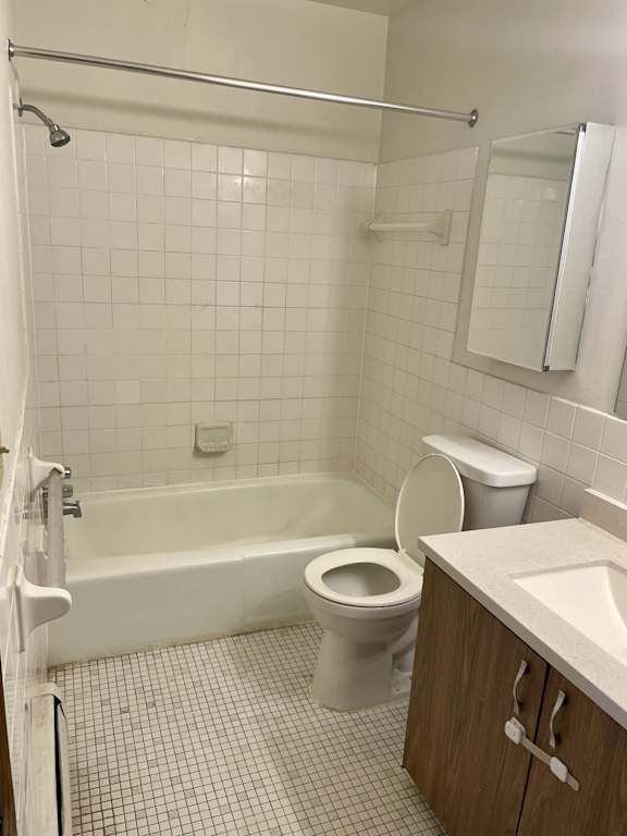 A white toilet sits in a bathroom next to a bathtub.