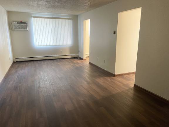 A room with wooden flooring and a window with blinds.