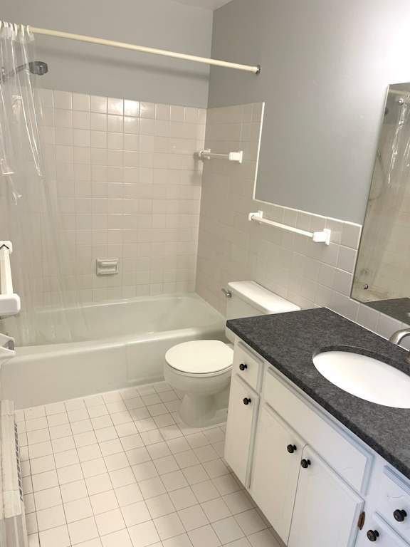 A white bathroom with a black counter top and white tiles.