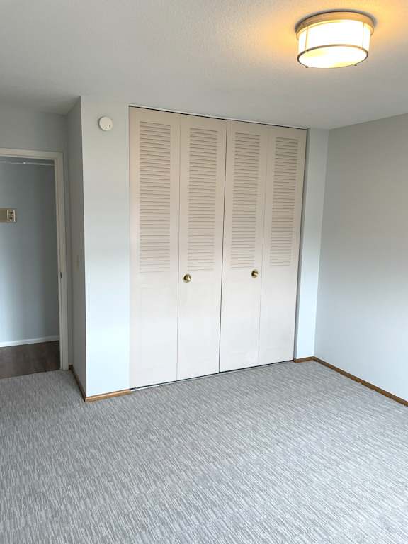 A room with a grey carpet and a white door with a light on.