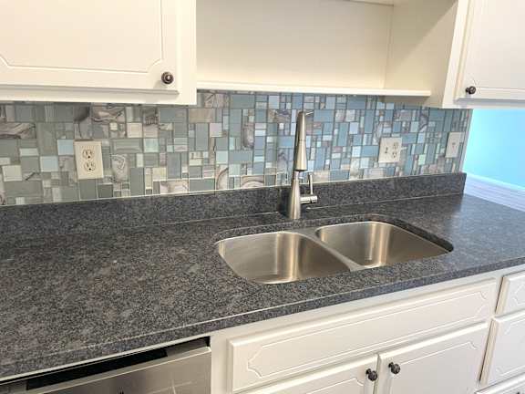 A kitchen with a sink and a tile backsplash.