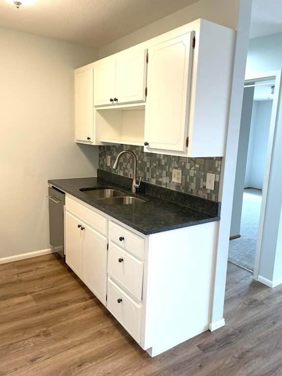 A kitchen with white cabinets and a black countertop.