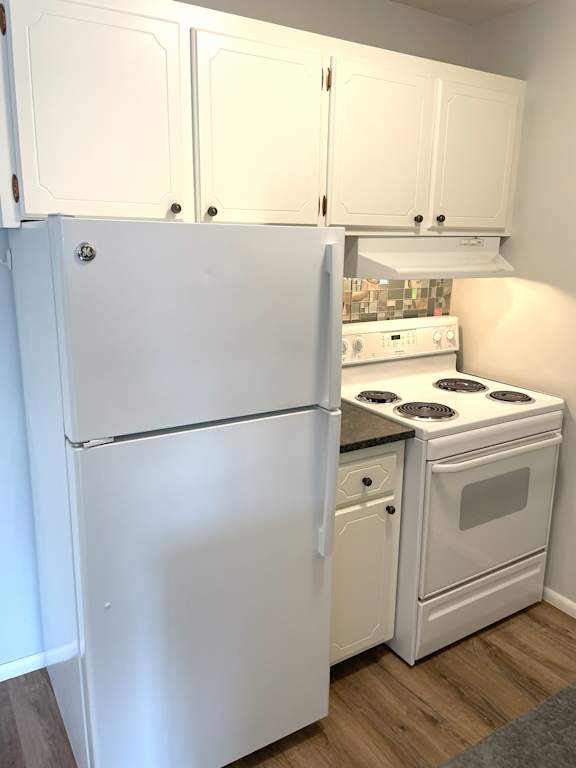 A white refrigerator and oven in a kitchen.