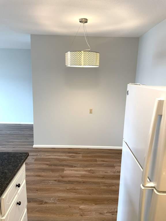 A kitchen with a white fridge and a wooden floor.