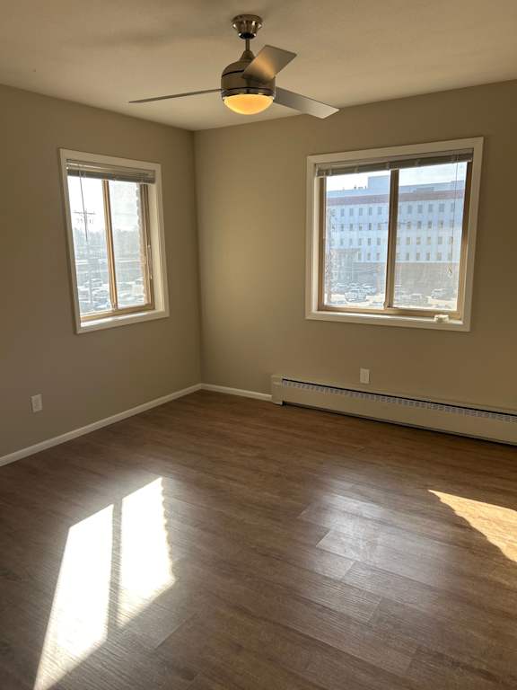 A room with a ceiling fan and two windows.
