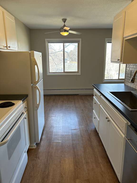 A kitchen with white cabinets and a black countertop.