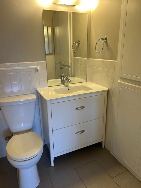 A white toilet sits next to a white sink in a bathroom.