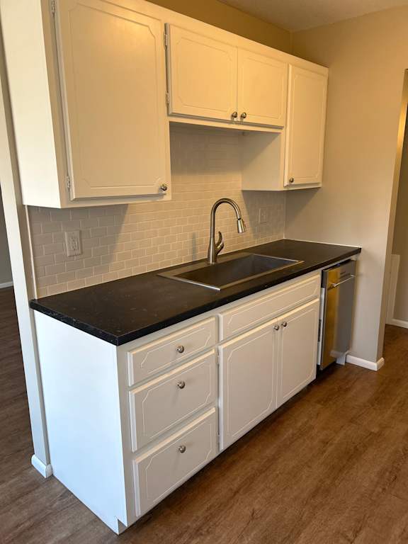 A kitchen with white cabinets and a black countertop.