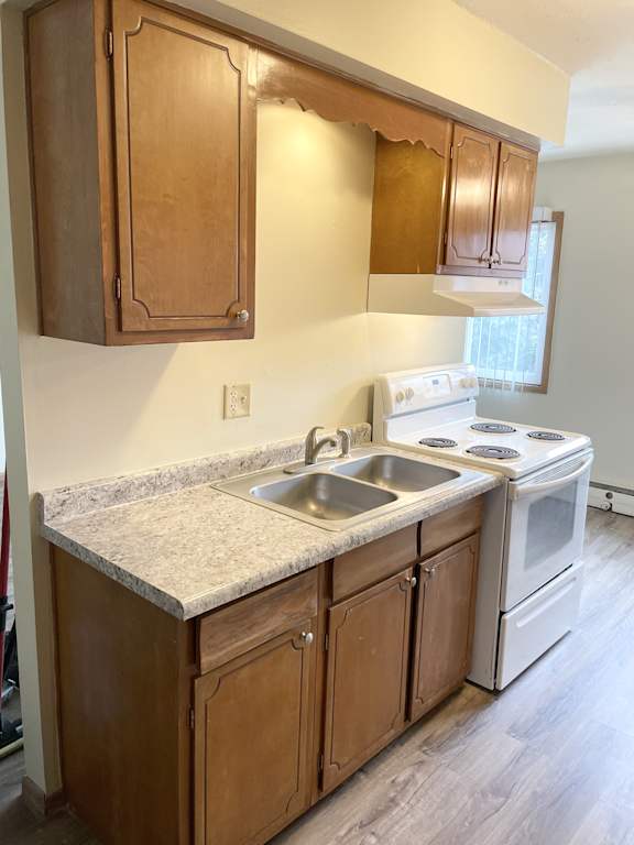 A kitchen with a white stove and wooden cabinets.