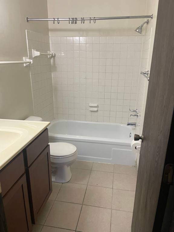 A white toilet sits in a bathroom next to a bathtub.