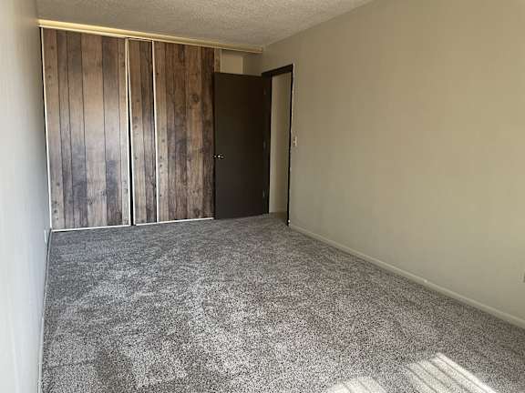 A room with a carpeted floor and a wooden wall panel.