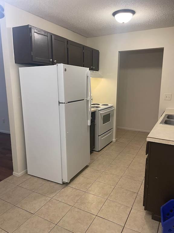 A kitchen with a white fridge and black cabinets.