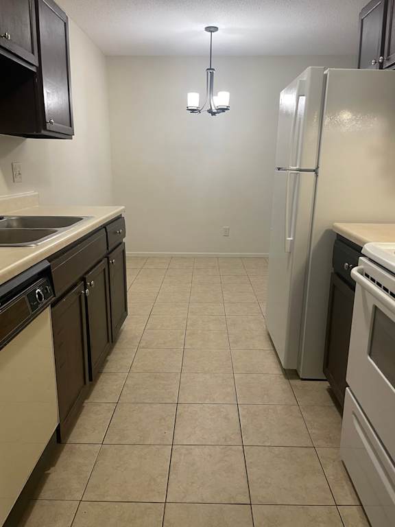 A kitchen with a white refrigerator, black cabinets, and a white sink.