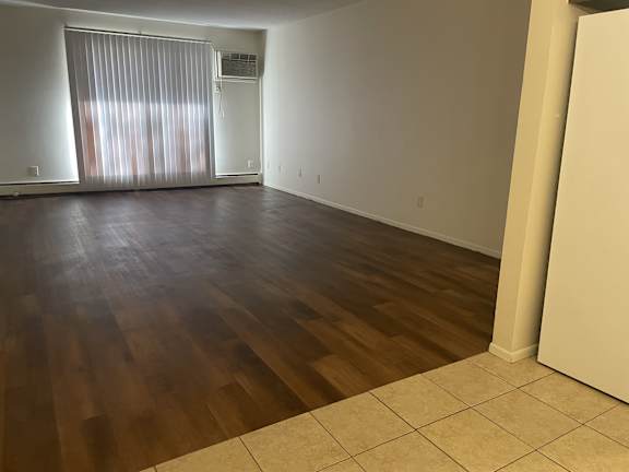 A room with wooden flooring and a window with blinds.
