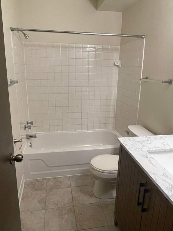 A white tiled bathroom with a toilet, tub, and sink.