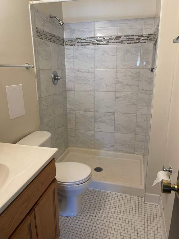 A white toilet is in a bathroom with a marble shower.