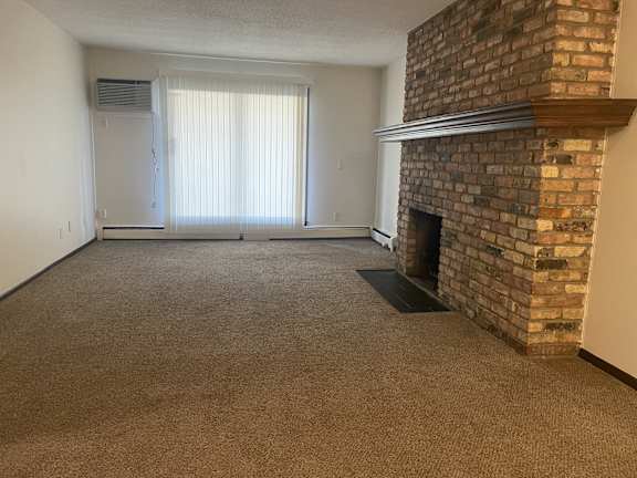 A room with a fireplace and a window with blinds.