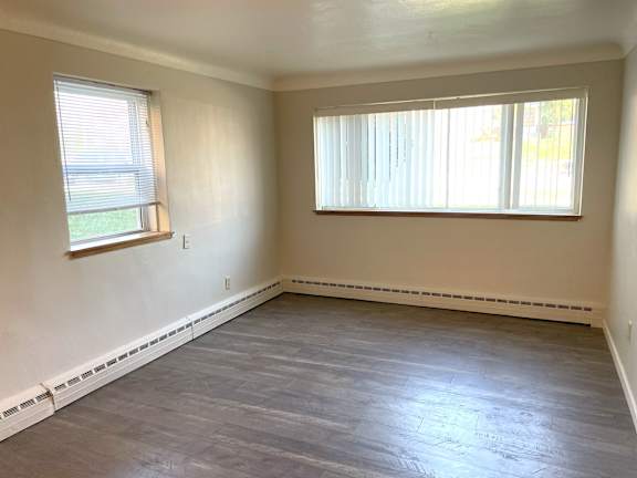 A room with a window and a wooden floor.