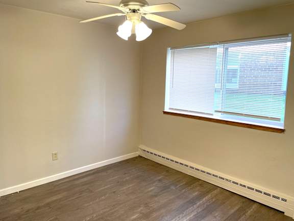A room with a ceiling fan and a window with blinds.