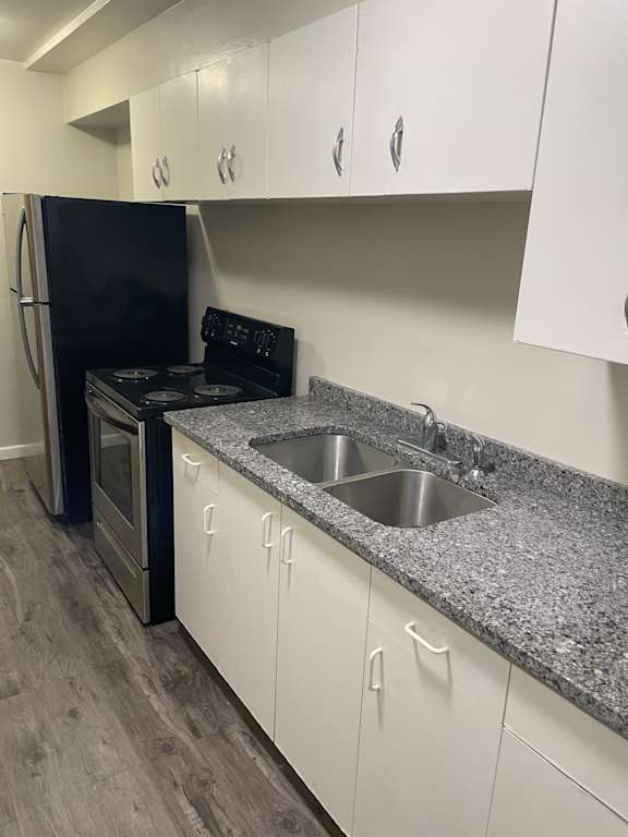 A kitchen with a black refrigerator and white cabinets.
