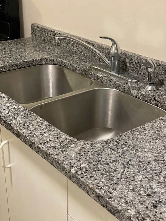 A granite countertop with a stainless steel sink and faucet.