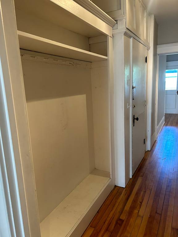 A long hallway with white walls and wood floors.