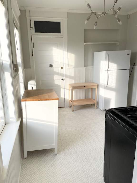 A kitchen with a black fridge and a wooden table.