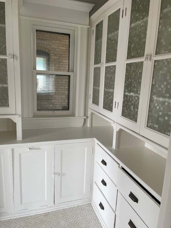A kitchen with white cabinets and a brick wall.